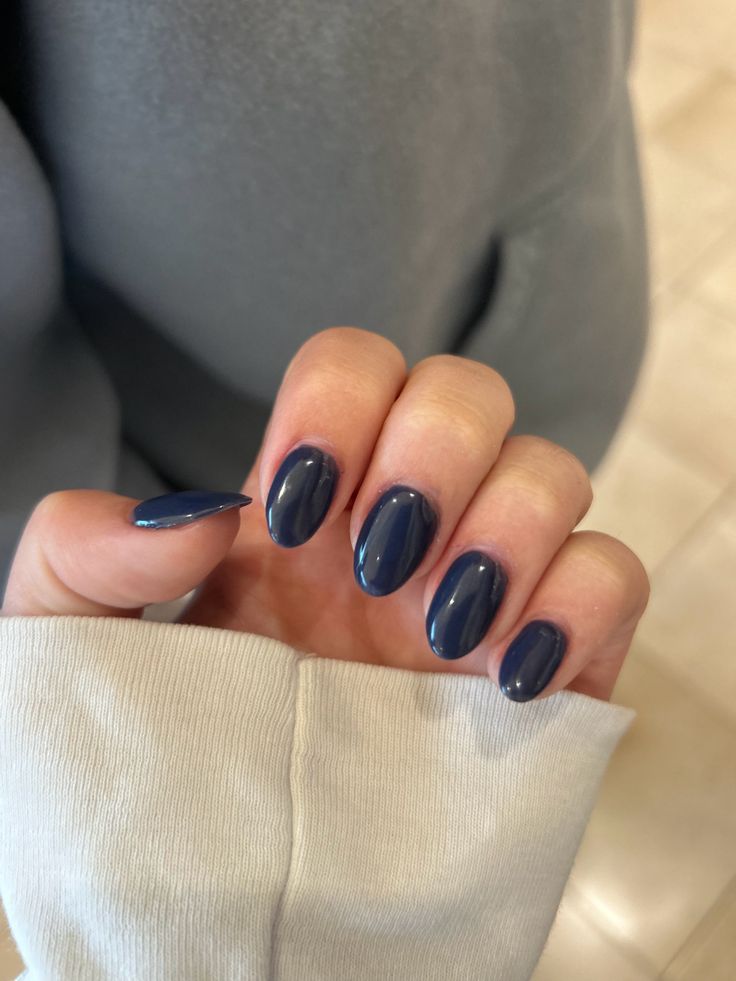 M&atilde;os femininas com unhas azul escuro