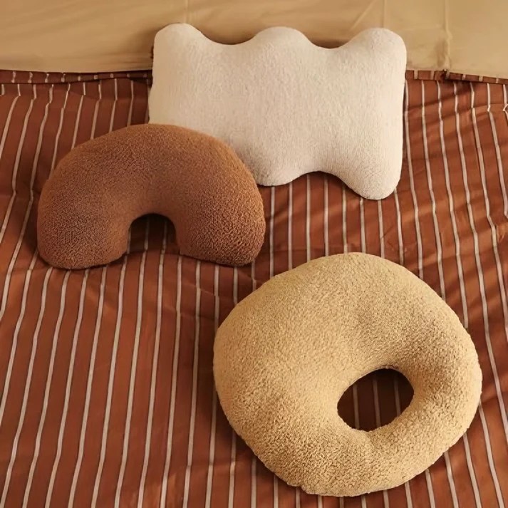 Três almofadas com tons terrosos e formas orgânicas