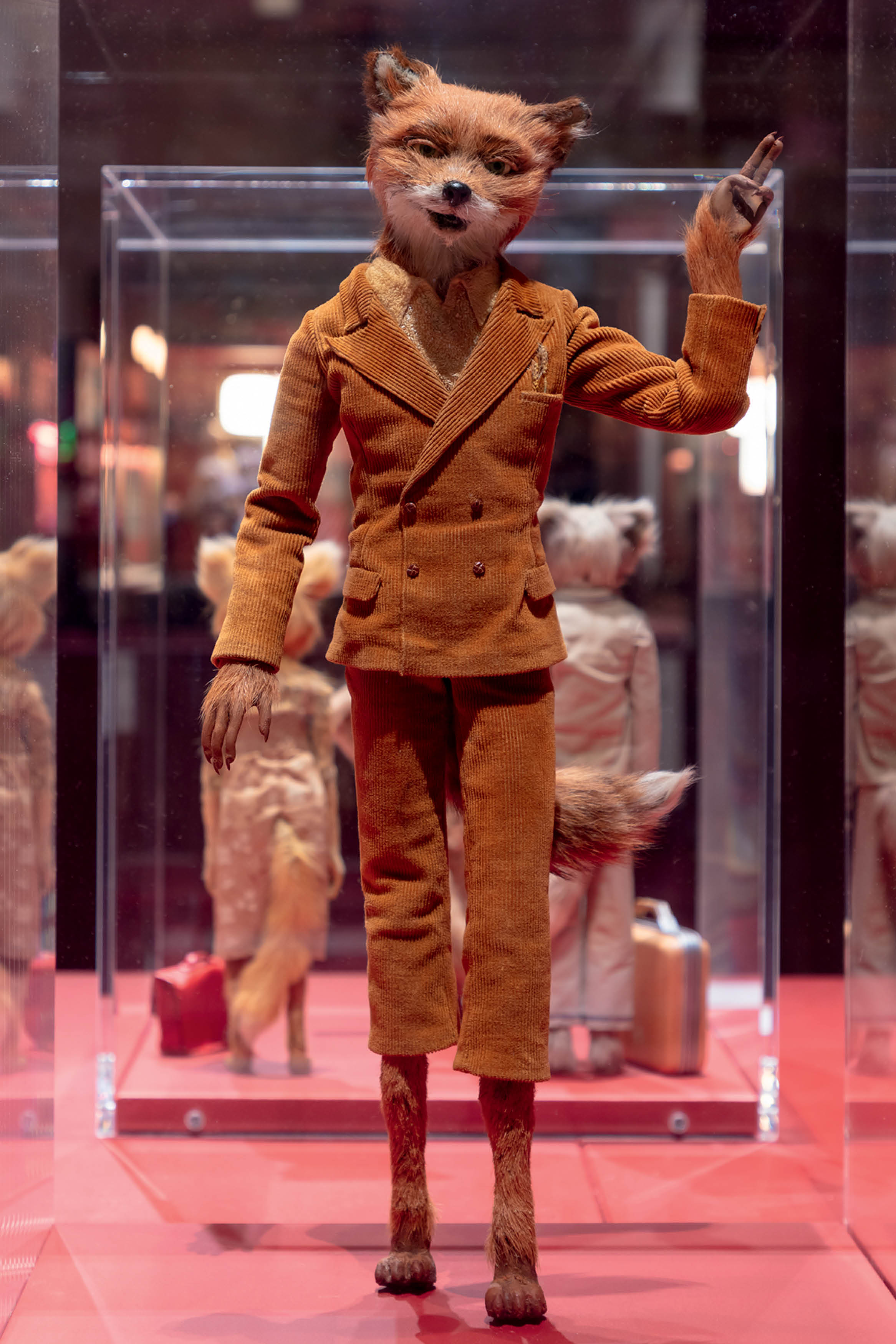 Figura estilizada de personagem em exposi&ccedil;&atilde;o com figurino detalhado, remetendo ao universo est&eacute;tico de Wes Anderson e sua influ&ecirc;ncia na moda e no design de figurino