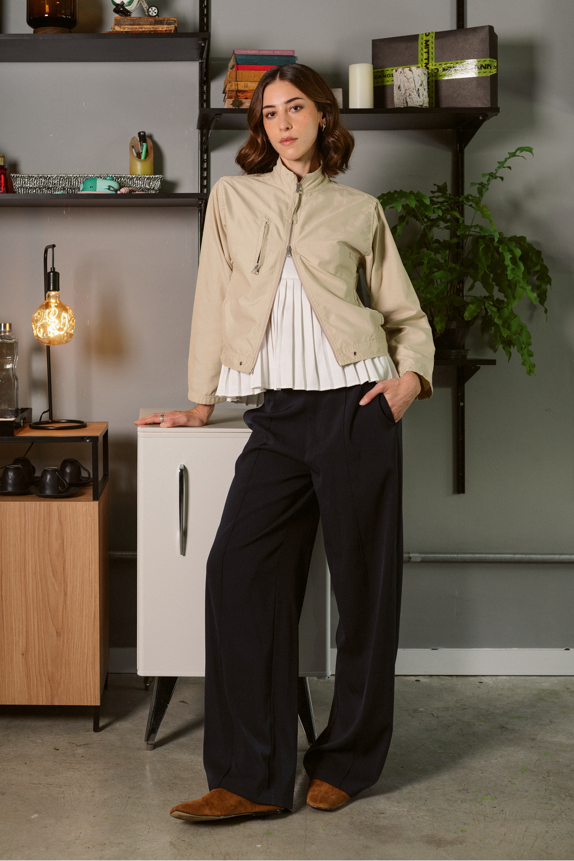 Foto de Alice Fleury. Ela &eacute; uma mulher morena, com cabelo curto, e usa um look composto por jaqueta, blusa branca, cal&ccedil;a preta e sapatilha marrom