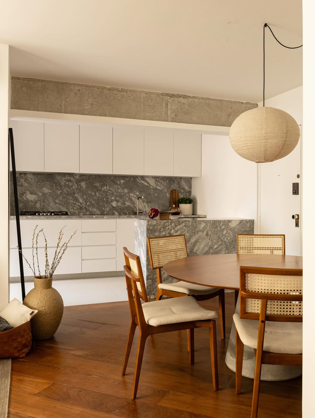 Sala e cozinha integradas com piso de madeira e parede de m&aacute;rmore