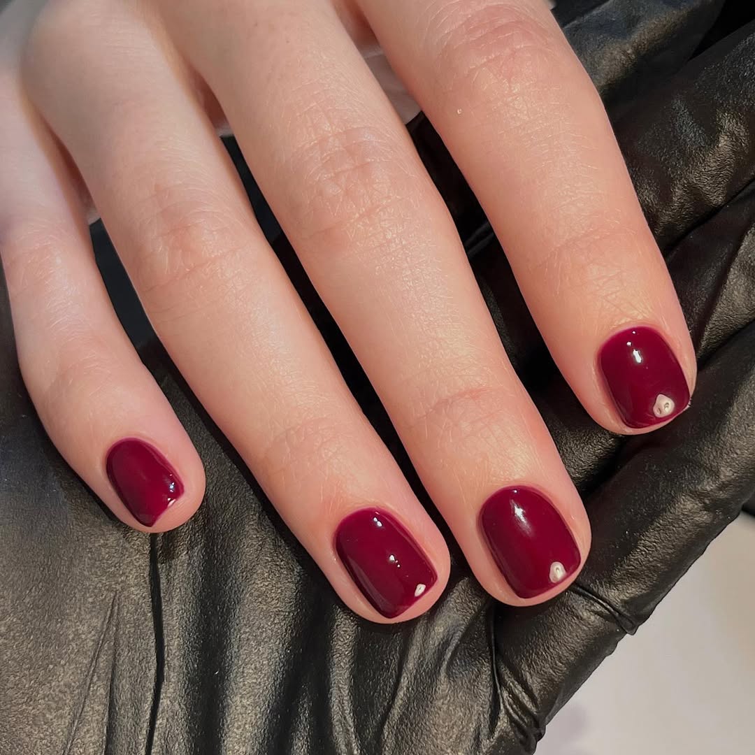 Foto de uma m&atilde;o com unhas coloridas de marsala