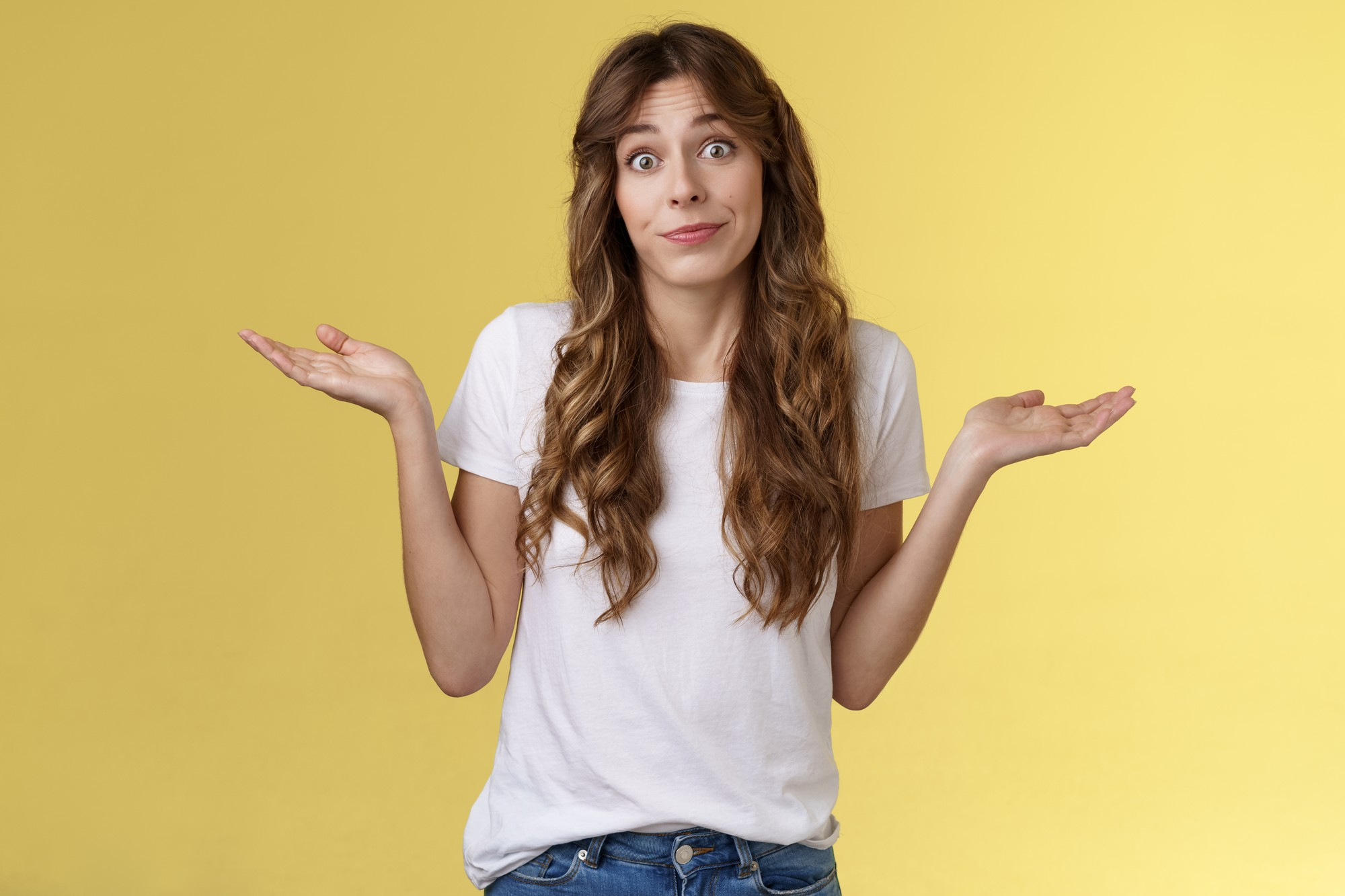 Mulher faz expressão de dúvida com os braços abertos contra fundo amarelo, ilustrando diálogo interno e questionamento mental.
