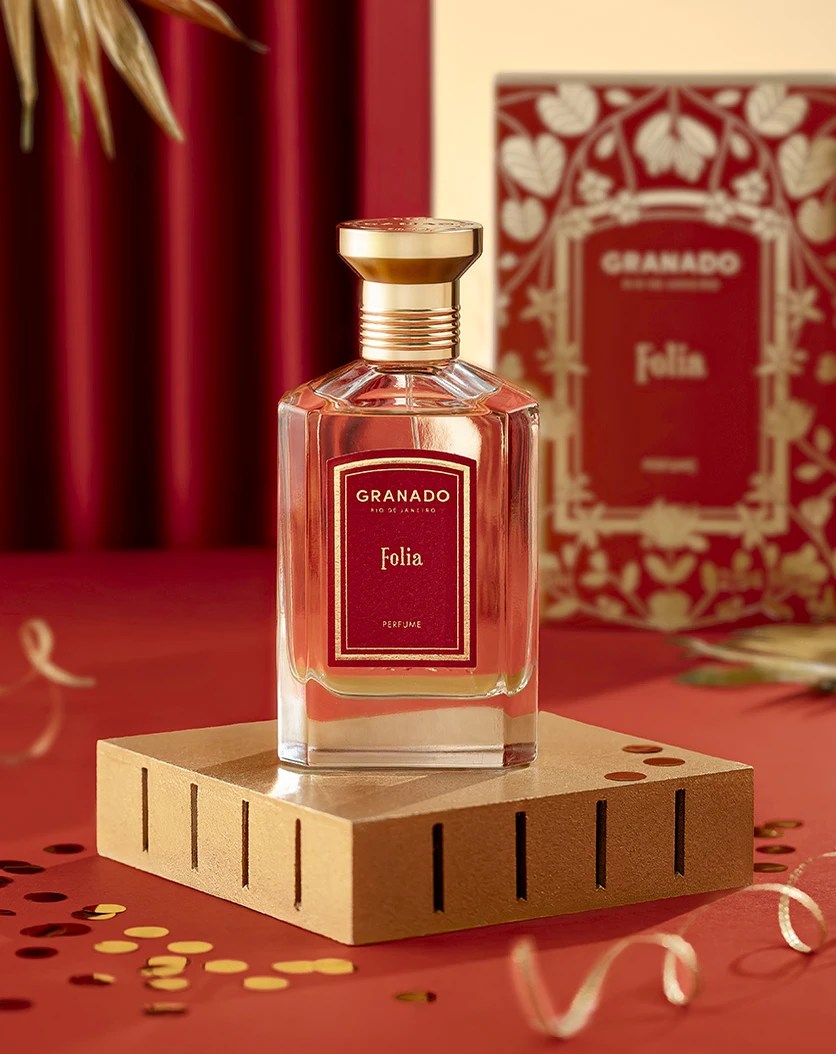 Perfume de embalagem retangular transparente, tampa dourada e líquido vermelho translúcido