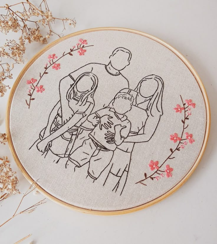 Bordado com ilustração de família em bastidor, decorado com flores.