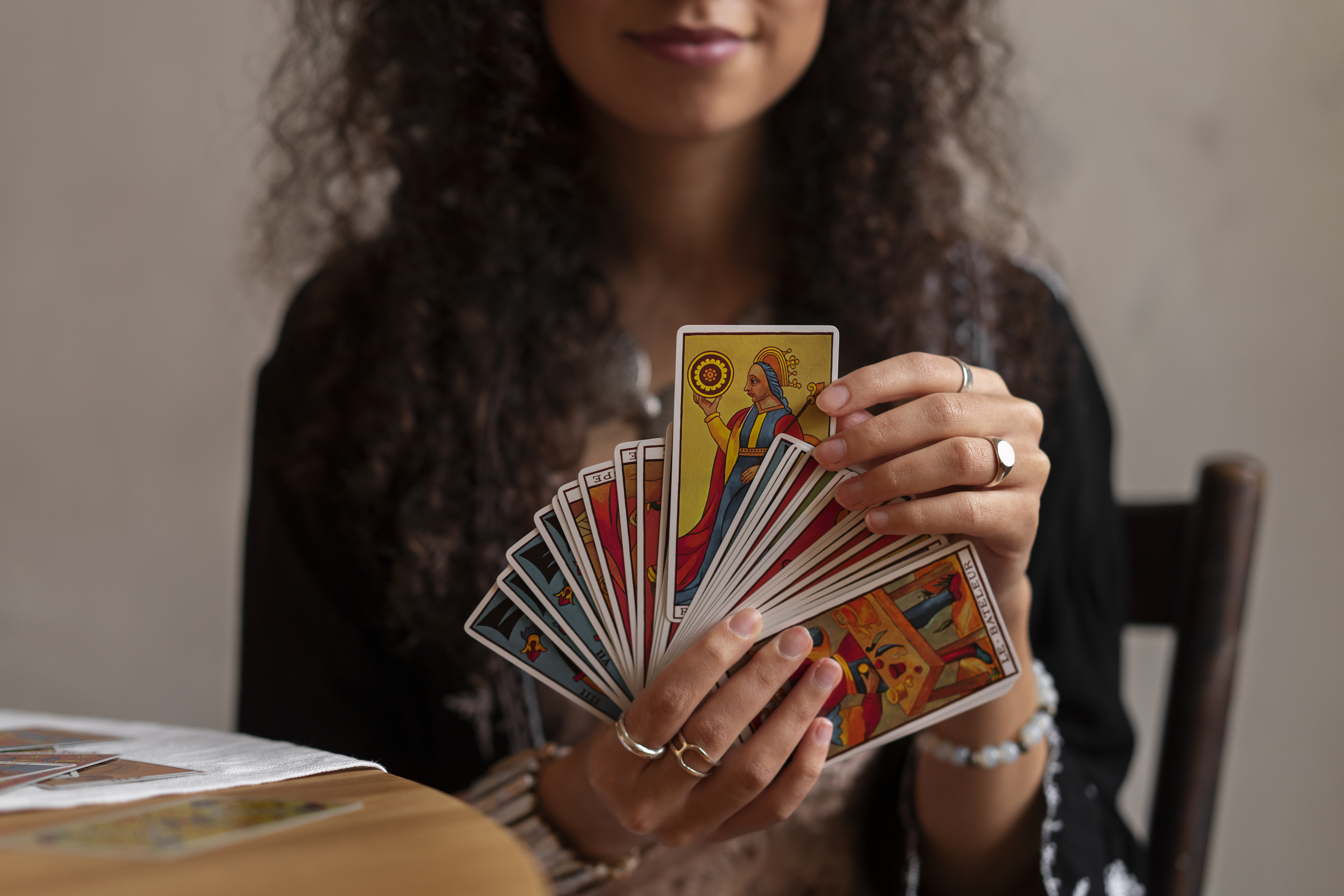 Mulher segurando cartas de tarot abertas nas mãos, representando leitura espiritual e descoberta do arcano pessoal ligado ao propósito de vida