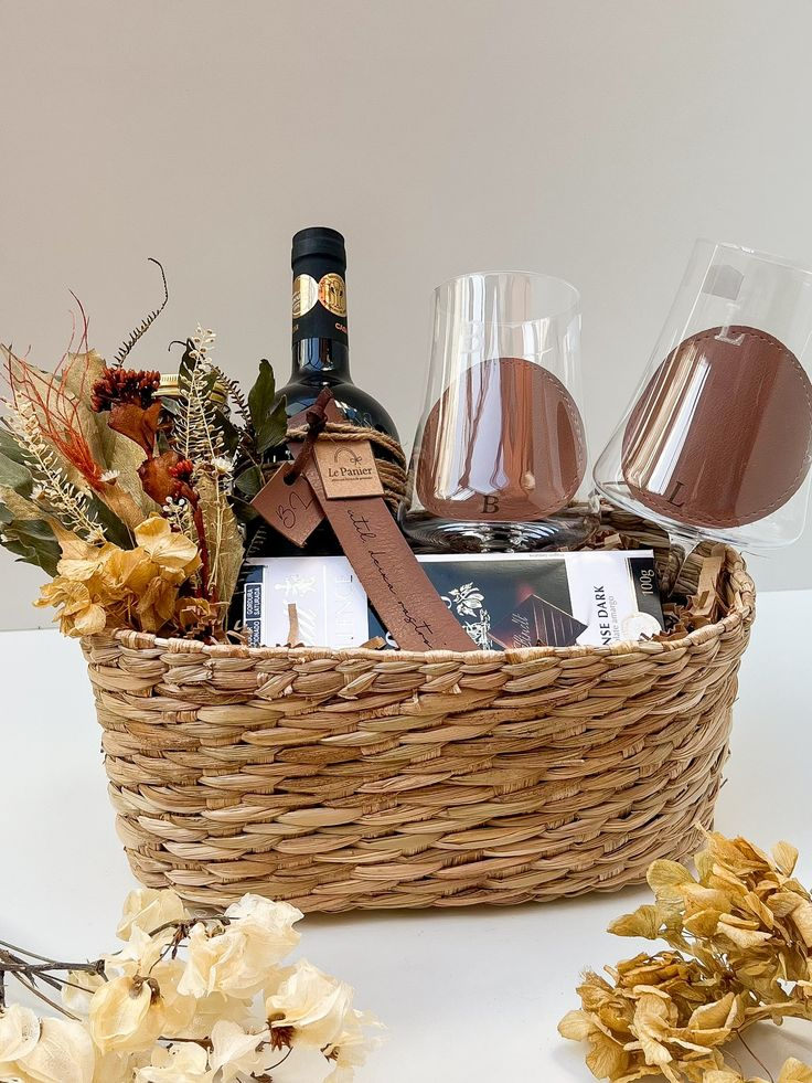 Cesta com garrafa de vinho, taças, chocolates e elementos decorativos em tons terrosos sofisticados.
