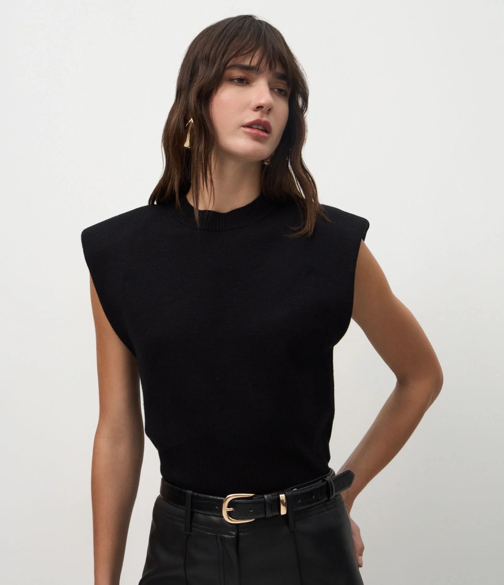 Foto de uma mulher morena usando um colete de tric&ocirc; preto