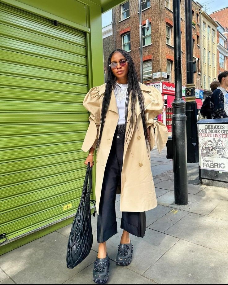 Produ&ccedil;&atilde;o de inverno combina trench coat bege, cal&ccedil;a preta ampla e crocs