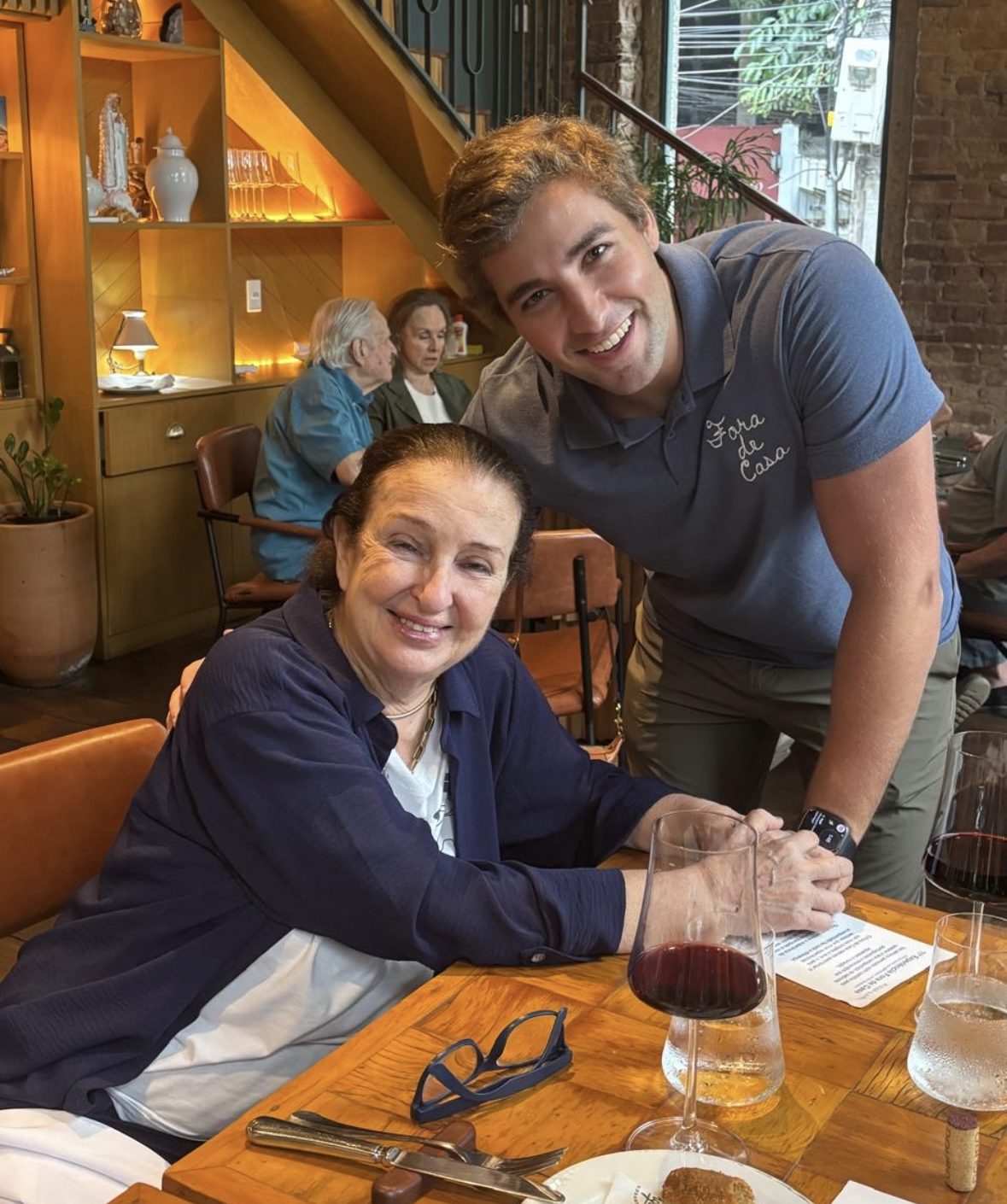 Jovem tirando foto com senhora sentada em mesa de restaurante