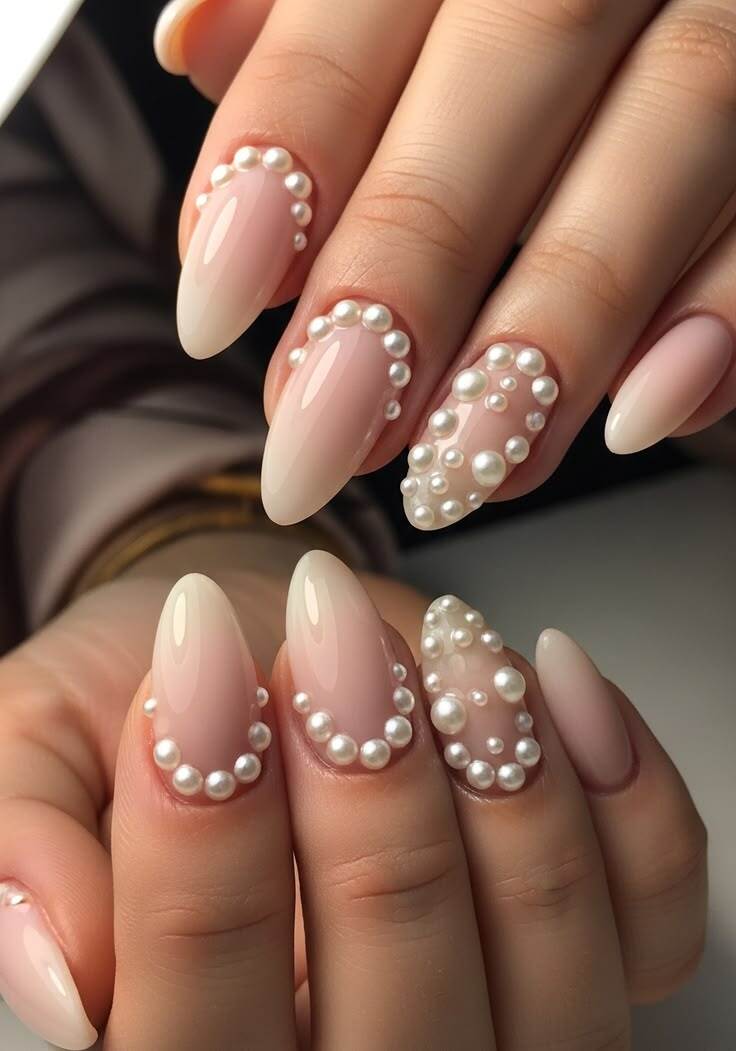 Unhas nude com aplica&ccedil;&atilde;o de p&eacute;rolas em formato amendoado, nail art delicada e sofisticada tend&ecirc;ncia maximalista 2026