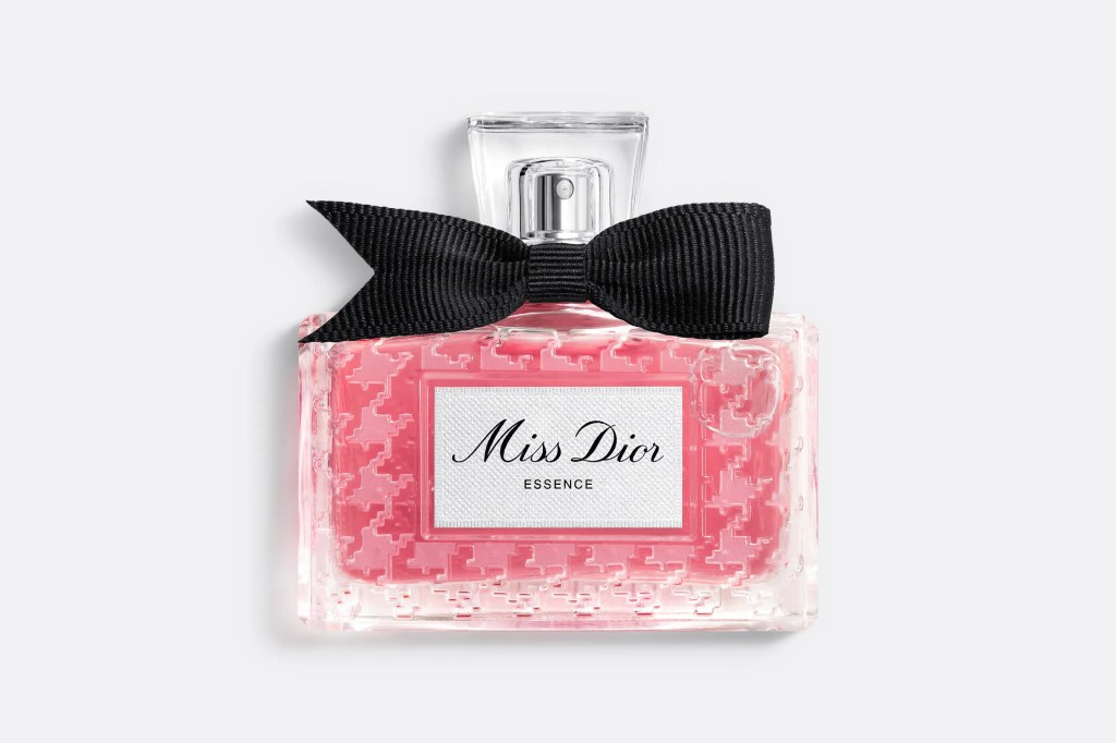 Frasco retangular de perfume Miss Dior Essence, com l&iacute;quido rosa claro e padr&atilde;o houndstooth em relevo, tampa transparente e la&ccedil;o preto de gorgor&atilde;o no gargalo