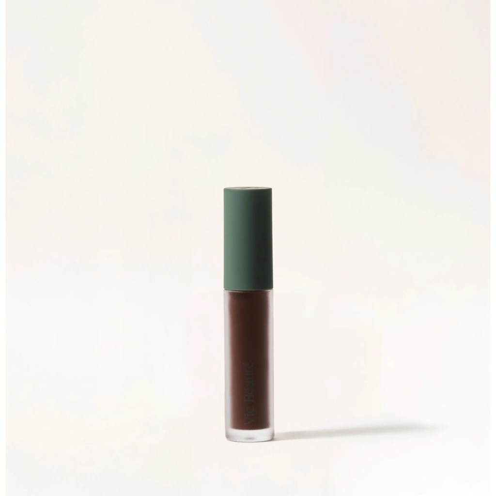 Um tubo de gloss labial marrom escuro com tampa verde-oliva, em fundo branco, projetando uma sombra sutil &agrave; direita