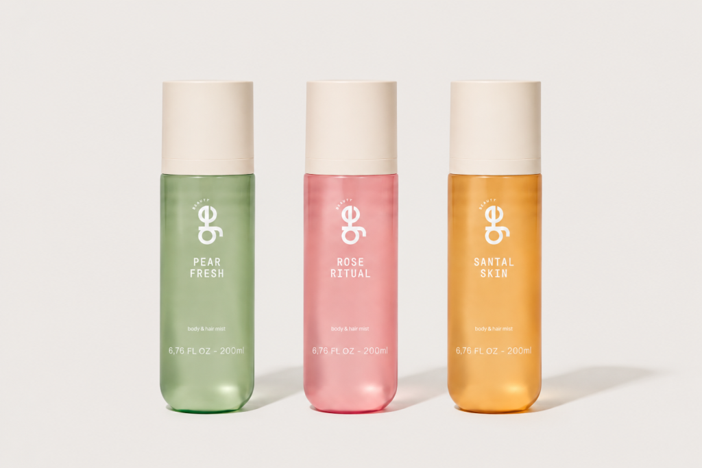 Tr&ecirc;s frascos de spray para corpo e cabelo da marca GE Beauty, com tampas bege. O primeiro &eacute; verde claro, com PEAR FRESH. O segundo &eacute; rosa, com ROSE RITUAL. O terceiro &eacute; laranja, com SANTAL SKIN. Todos indicam 200ml