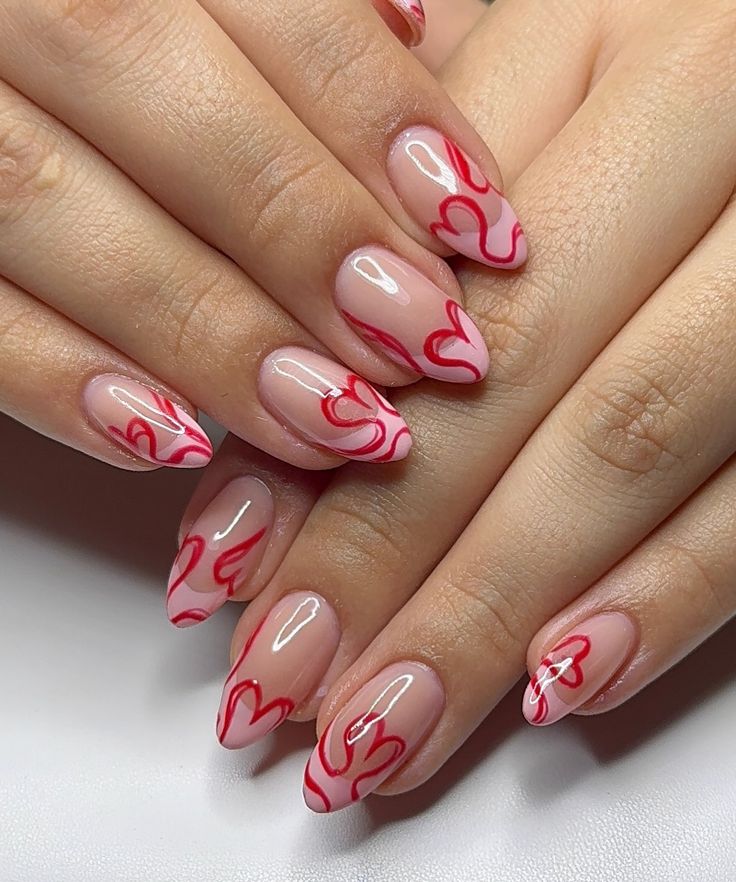 M&atilde;os com unhas ovais longas, esmaltadas em tom nude transl&uacute;cido com desenhos de chamas vermelhas vibrantes em cada unha