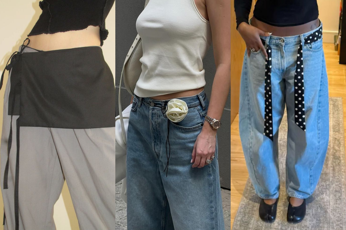 Três mulheres exibem tendências de moda com calças de cintura baixa. A primeira usa calça cinza e top preto com faixa preta amarrada na cintura. A segunda veste jeans largo, top branco, relógio prateado e flor branca presa na calça. A terceira usa jeans folgado, top preto, cinto de bolinhas e sapatos pretos