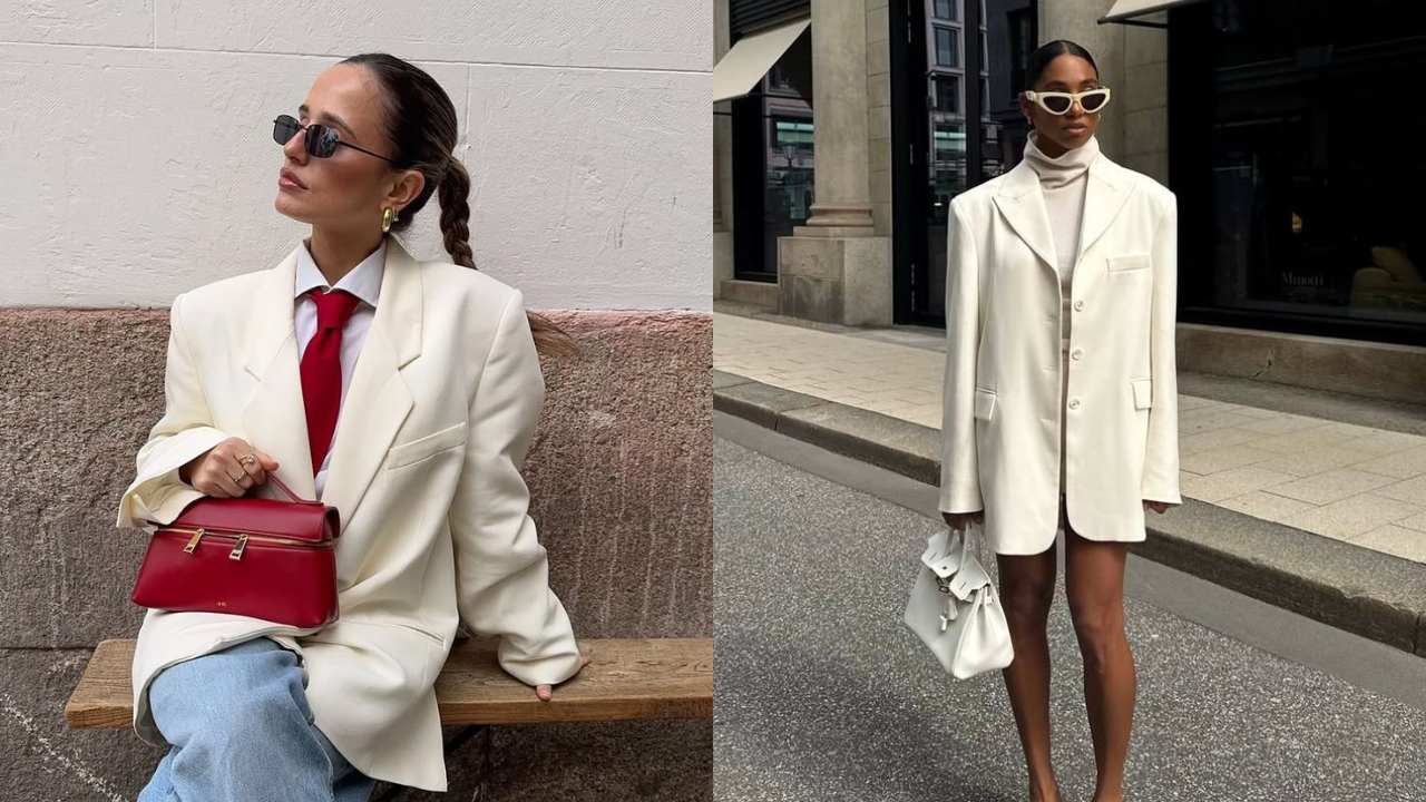 Duas mulheres exibem blazers creme oversized. À esquerda, uma mulher sentada usa gravata vermelha, jeans e óculos escuros, segurando uma bolsa vermelha. À direita, outra mulher em pé veste gola alta creme, óculos de sol brancos e segura uma bolsa branca, em frente a um prédio urbano